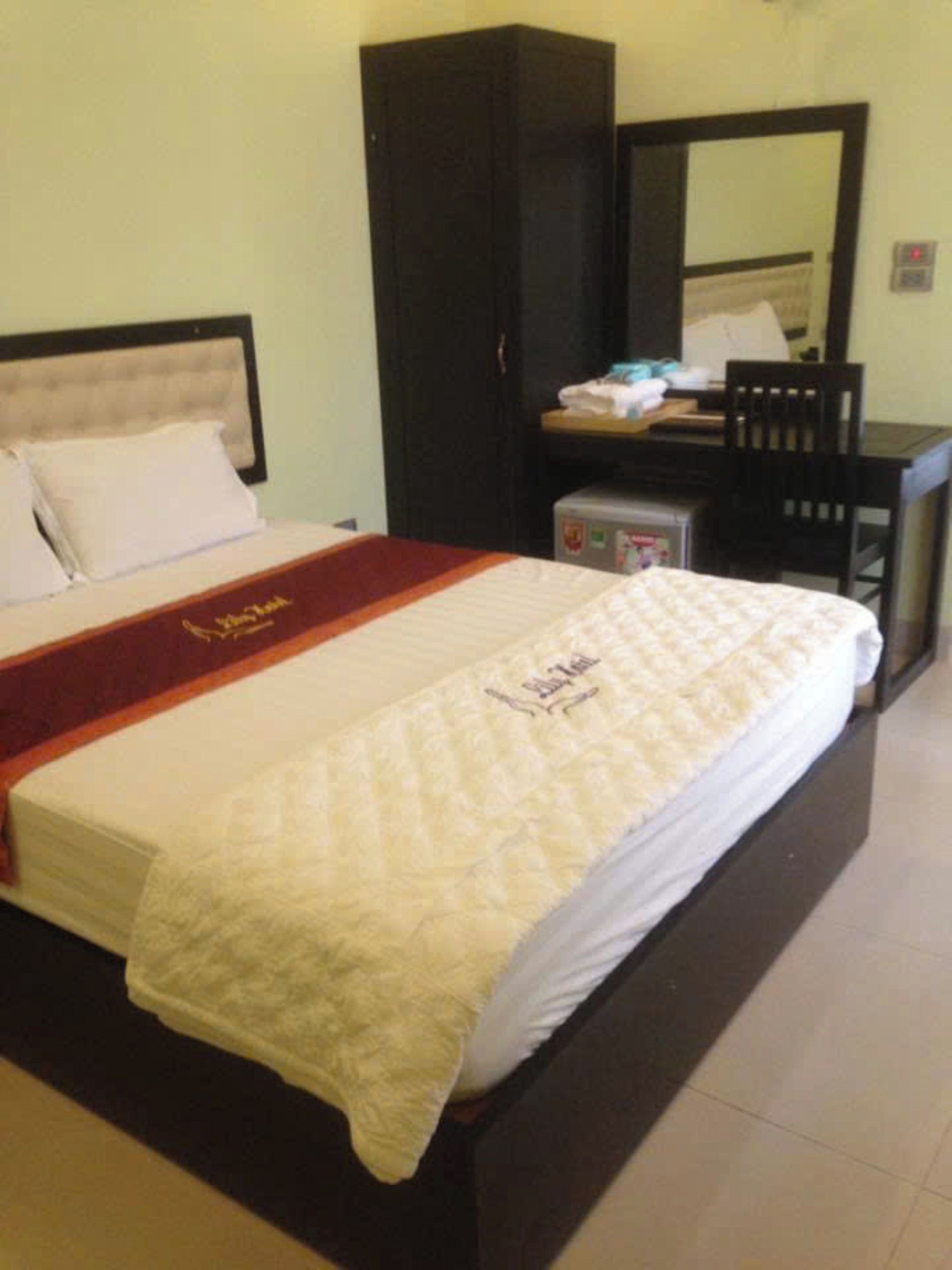 A hotel room with a bed, a wardrobe, a desk, and a chair.