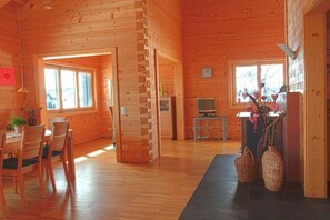 Un intérieur en bois comprenant un coin repas, un téléviseur et une cheminée.