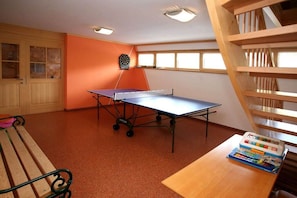 Ein Zimmer mit einem Tischtennis-Tisch, einer Dartscheibe, einem Bücherregal und einem Fenster mit Blick.