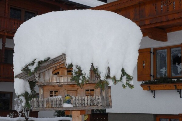 Een houten chalet met balkon, omgeven door sneeuw.