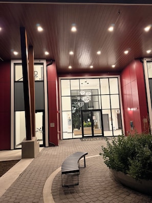 A building entrance with a glass door, a bench, and a planter with greenery. - Corporate 90+Day | 2BR&2BA | Travel Professionals (Surrey)