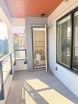 Un balcon doté d’une porte-fenêtre coulissante donnant sur une pièce intérieure, d’un petit climatiseur et offrant une vue sur l’extérieur.