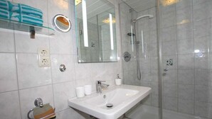 A bathroom with a white sink, a glass shower enclosure, a mirror, and a towel rack. - Penkenblick in the Tasser House (Mayrhofen)
