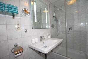 A bathroom with a white sink, a glass shower enclosure, a mirror, and a towel rack. - Penkenblick in the Tasser House (Mayrhofen)