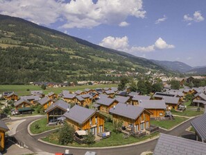A cluster of wooden cabins with sloped roofs, surrounded by green fields and mountains in the background. - Cabin With 1 Bedroom (Sankt Georgen am Kreischberg)