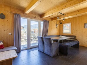 Ein Holzinnenraum mit Esstisch, Bänken und Blick durch eine Glastür.