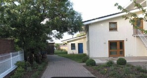 Een woongebouw met een verharde oprit, een bakstenen muur en een boom.
