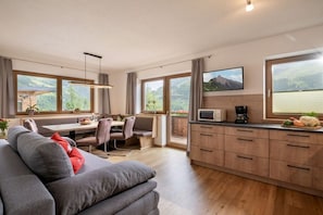 A modern kitchen with a dining area, large windows, and a view of the outdoors. - Kolm in Christina's country house (Mayrhofen)