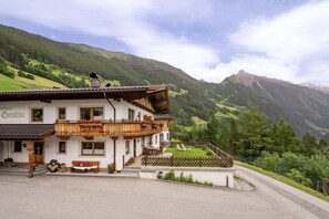 A traditional chalet with a balcony, a small garden, and a mountain backdrop. - Kolm in Christina's country house (Mayrhofen)