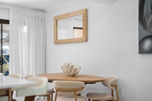 A dining area with a wooden table, white chairs, and a decorative shell centerpiece. - Jindiburra Coastal Haven at Noosaville (Noosaville)