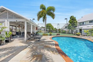 Ein Swimmingpool mit Liegestühlen und einer überdachten Sitzgelegenheit.