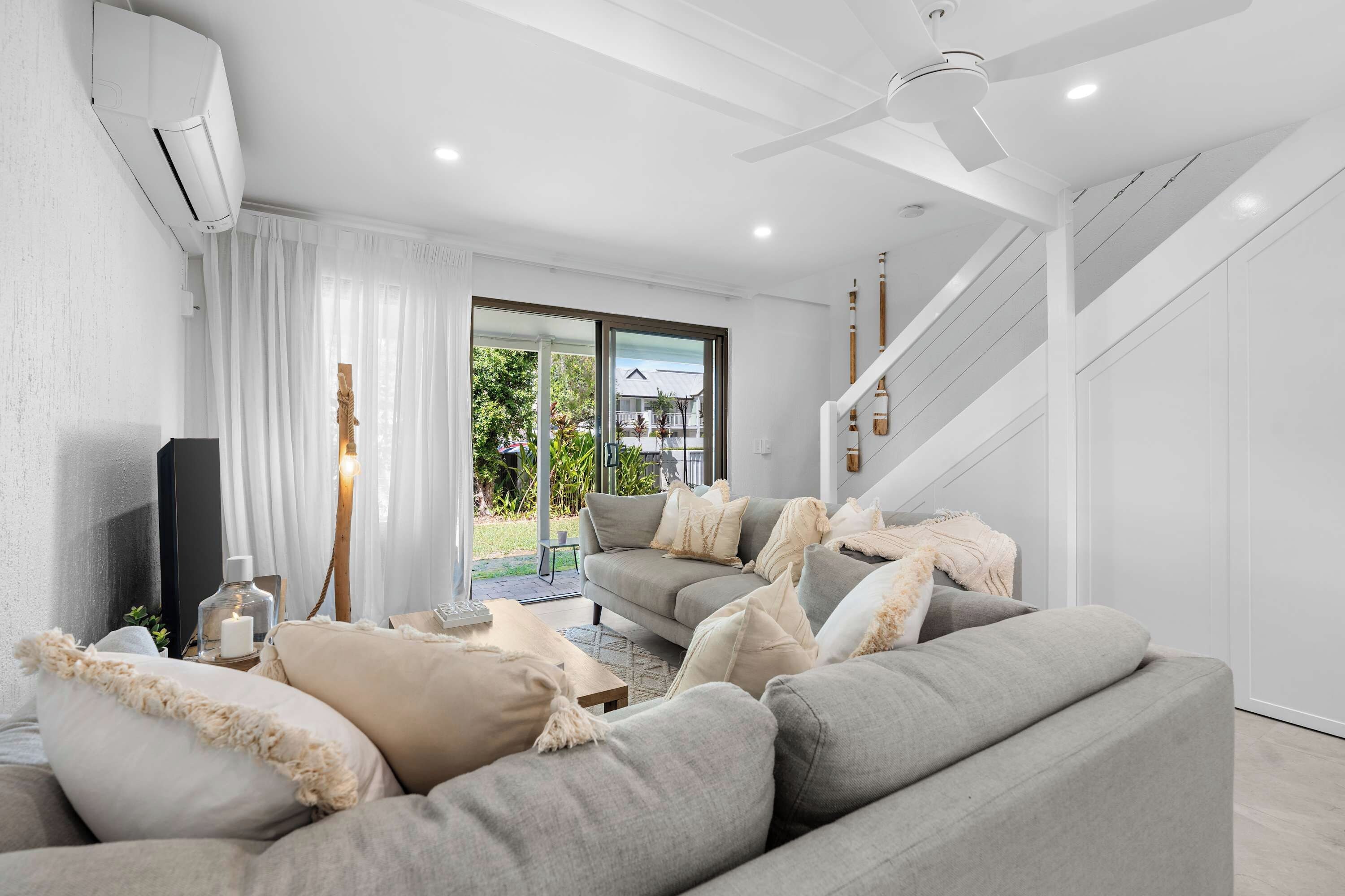 A modern living room with a grey sofa, a TV, and a ceiling fan.