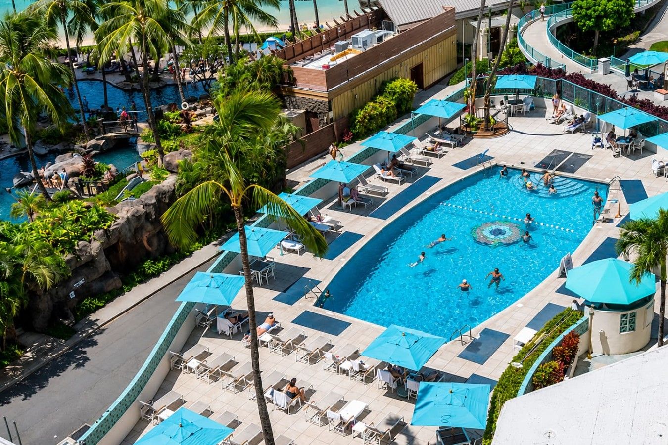 Um resort com várias piscinas, áreas de descanso e palmeiras.