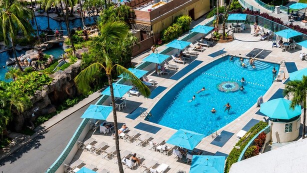 Een resort met meerdere zwembaden, terrasjes en palmbomen.