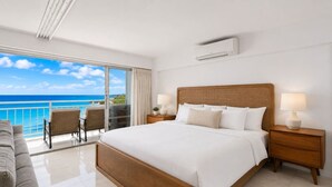 Una habitación de hotel con una cama grande, una mesita de noche, una lámpara, una silla y vistas al océano.