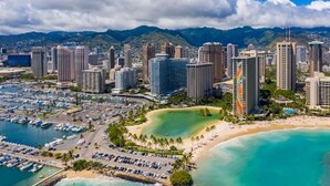 Un paisaje urbano costero con rascacielos, un puerto deportivo y una playa.
