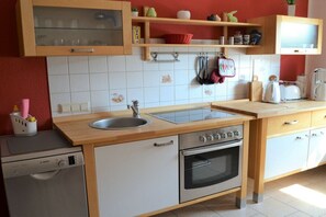 Una cocina compacta con lavavajillas Bosch, horno empotrado y un lavamanos.