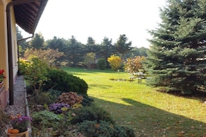A garden with a lawn, a table, and a variety of plants and trees. - Holiday apartment with 2 bedrooms (Ostseebad Heringsdorf)