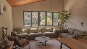 Uma sala de estar moderna com sofá, mesa de centro e mesa de madeira.