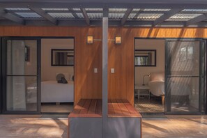 A modern interior with a wooden bench, a bed, and a desk area. - Private Hinterland Cabin near Beaches & Rail Trail: Cabin 2 (Burringbar)