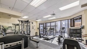 A gym with various exercise equipment, large windows, and a carpeted floor. - Luxe Retreat – Modern Coastal Comfort (Honolulu)
