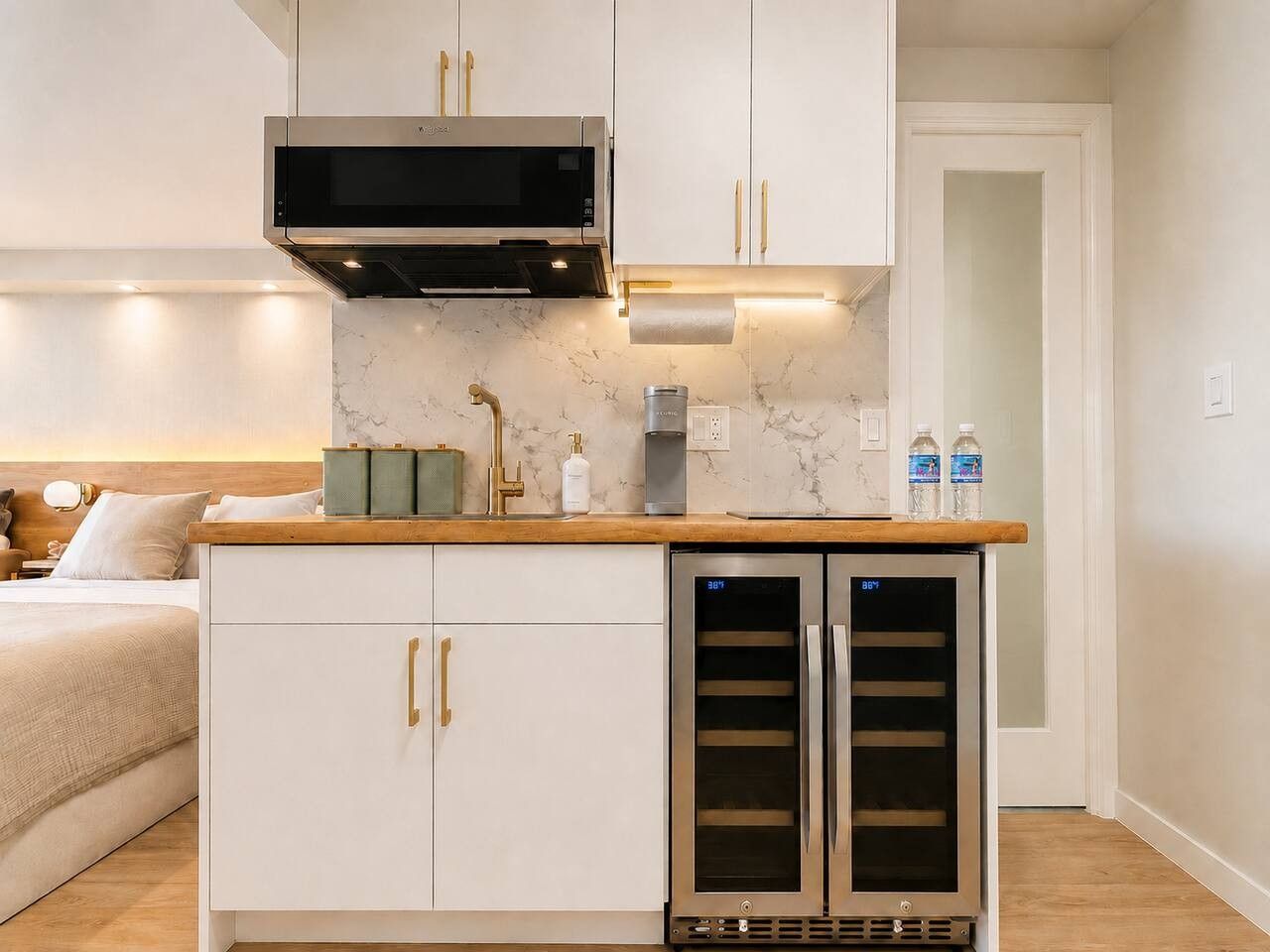 A compact kitchenette with a microwave, a built-in oven, and a wine cooler.