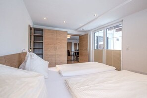 A modern bedroom with a bed, a wardrobe, and a desk area. - 60 m² Guesthouse Sonne (Bichlbach)