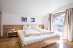Ein Schlafzimmer mit einem hölzernen Bett, einem Nachttisch mit Lampe und einem Fenster mit Vorhängen.