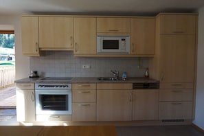 A kitchen with wooden cabinets, a built-in microwave, a sink, and a dishwasher. - Holiday apartment with 4 bedrooms (Schoppernau)