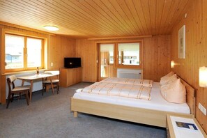 Een kamer met houten vloeren, een bed, een bureau en een televisie.