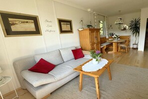 Ein Wohnzimmer mit einer Couch, einem Holztisch und einem Essbereich.