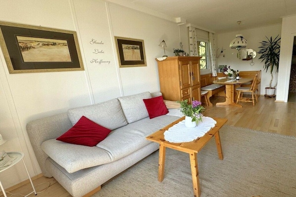 A living room with a sofa, a wooden table, and a dining area.