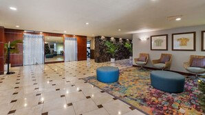 A hotel lobby with a check-in desk, seating area, and a reception desk. - New Waikiki Studio | King | Parking | Pool (Honolulu)