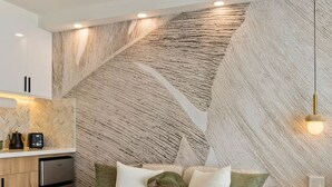 A modern living room with a sofa, a coffee table, and a textured wall. - New Waikiki Studio | King | Parking | Pool (Honolulu)
