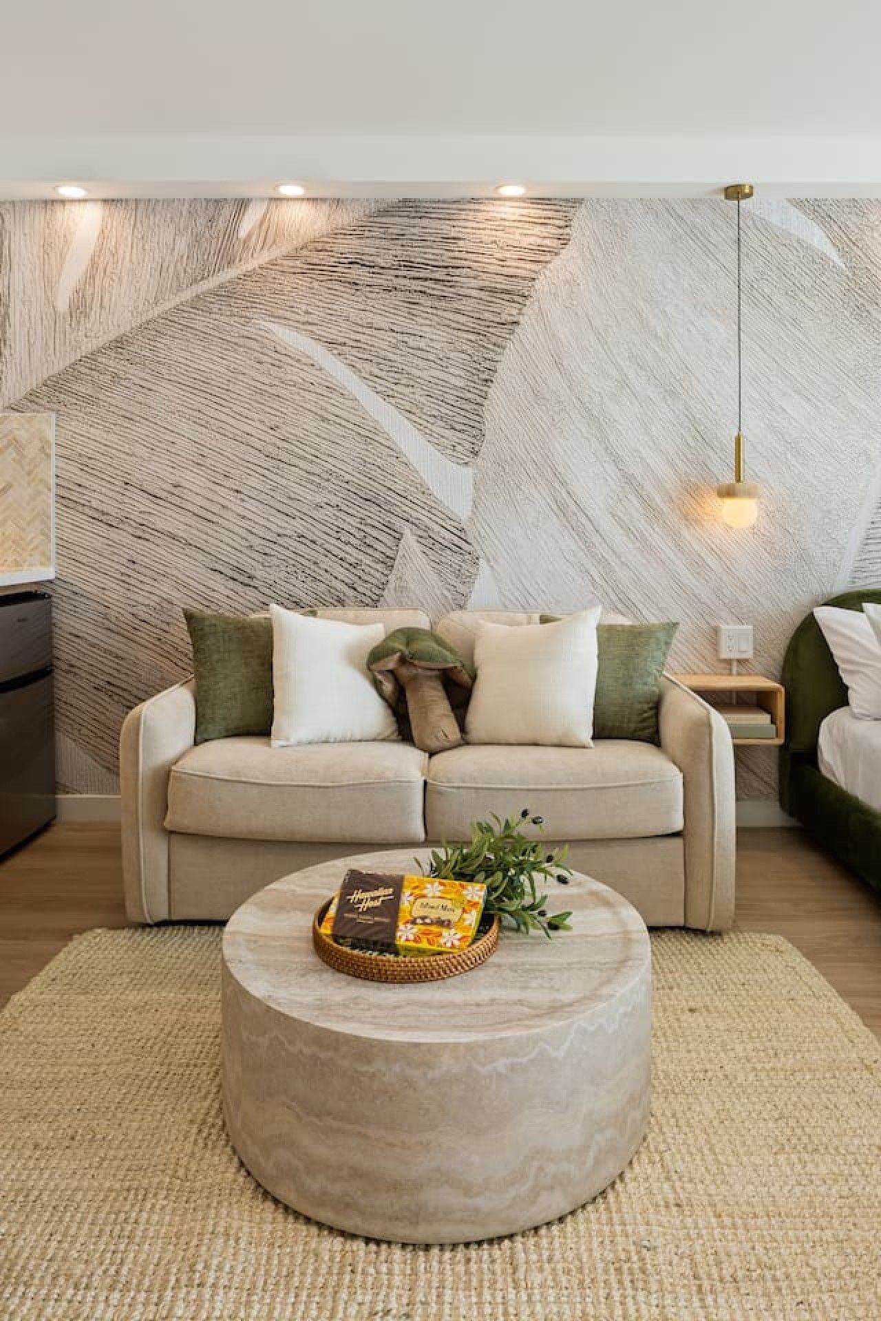 A living room with a sofa, a coffee table, and a wall with a geometric pattern.