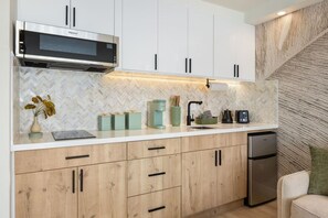 Una cocina moderna con microondas integrado, armarios de madera y salpicadero con estampado de espiga.