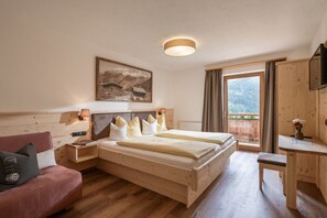 Ein Schlafzimmer aus Holz mit einem Bett, einem Schreibtisch, einem Stuhl, einem Sofa und einem Fenster mit Vorhängen.