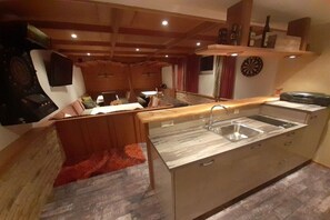 A kitchen with a wooden countertop, a sink, and a dining area with a table and chairs. - Holiday home with 1 bedroom (Zell am Ziller)
