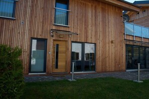 Ein Holzgebäude mit Schiebeglaseingang, einem kleinen Fenster und einer Satellitenschüssel.