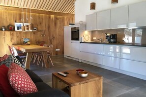 Eine moderne Küche mit weißen Schränken, einem Holztisch und einer Kaffeemaschine.