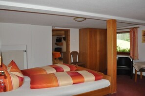 Ein Schlafzimmer mit einem Bett, einem Holzschrank, einem Sessel und einem kleinen Tisch.