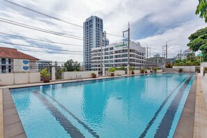A swimming pool with a view of a hotel building in the background. - Pratumnak Hill 2BR Sea View (PH3) (Banglamung)