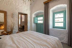 Un dormitorio con cama, chimenea de piedra, ventana con cortinas y puerta con vistas al exterior.