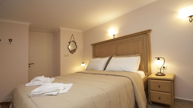 A hotel room with a bed, bedside lamps, a nightstand, and a door. - Kaminos Boutique Hotel (Symi)