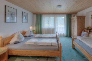 Ein Zimmer mit einem hölzernen Bett, einem Holzschrank und einem Fenster mit Vorhängen.