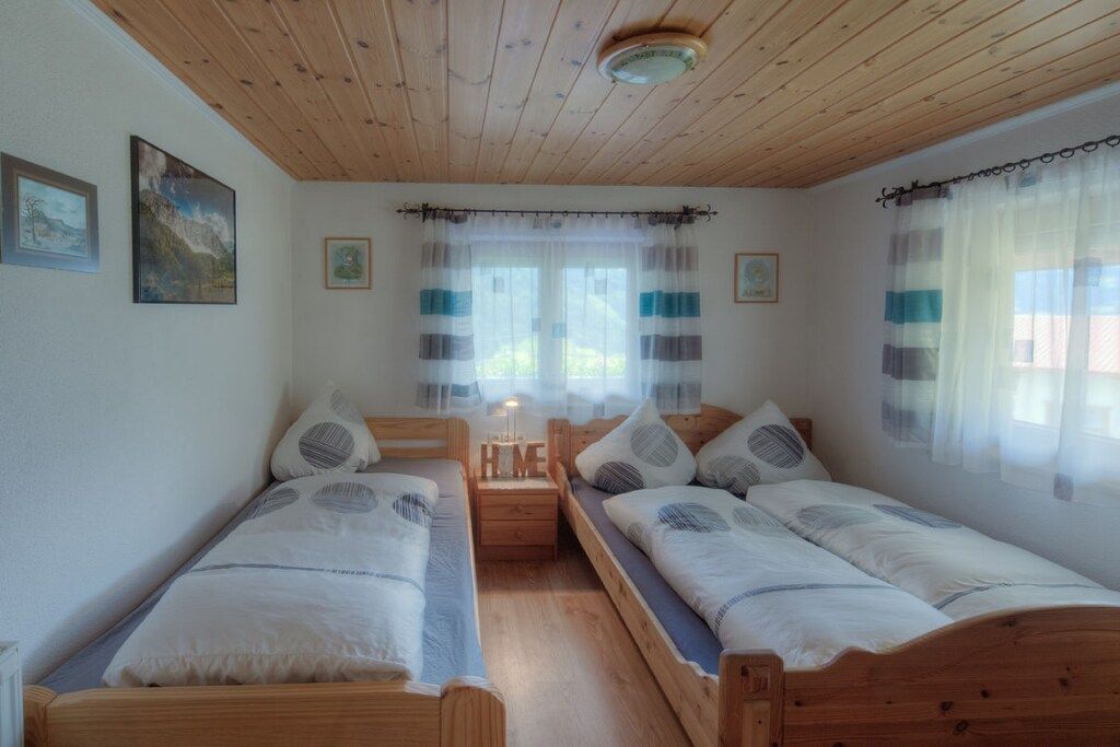 A bedroom with two wooden beds, a nightstand, and a window with curtains.