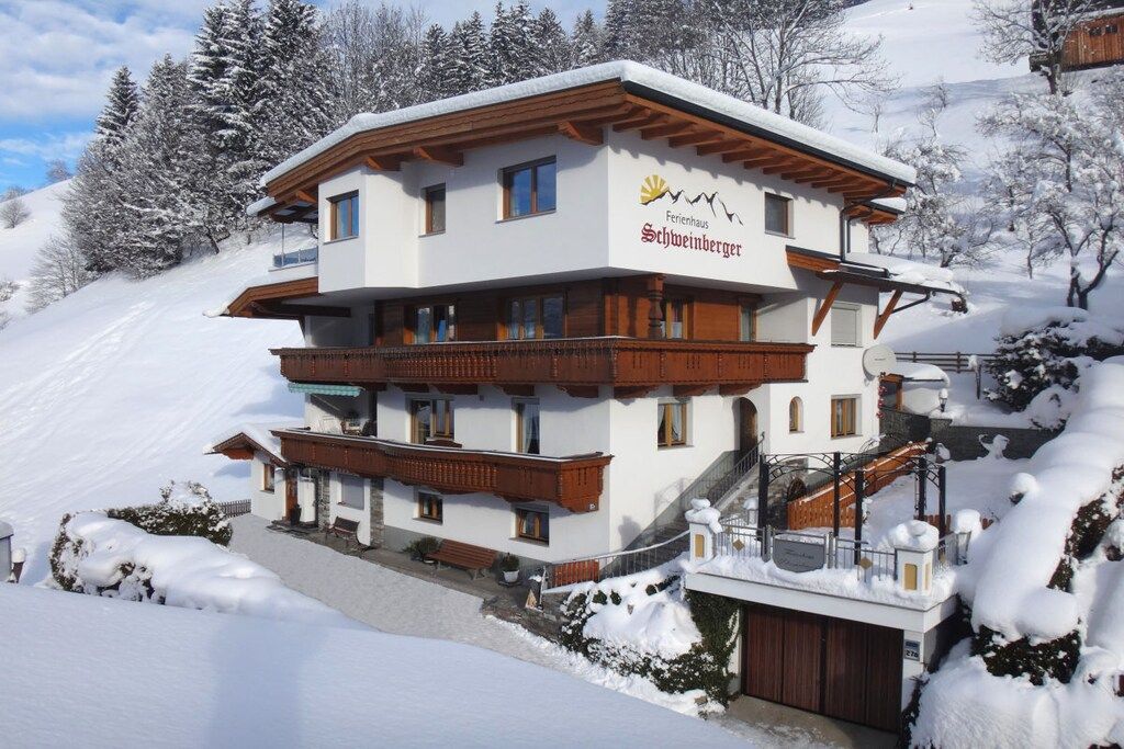 A multi-story hotel with a ski lift, surrounded by snow-covered trees.