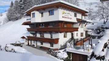 A multi-story hotel with a ski lift, surrounded by snow-covered trees.