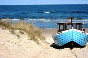 Um barco chamado HER.12 numa praia arenosa, com o oceano ao fundo.