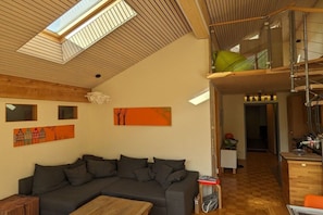 A modern living space with a wooden ceiling, a grey sofa, and artwork on the walls. - Holiday apartment with 3 bedrooms (Schröcken)